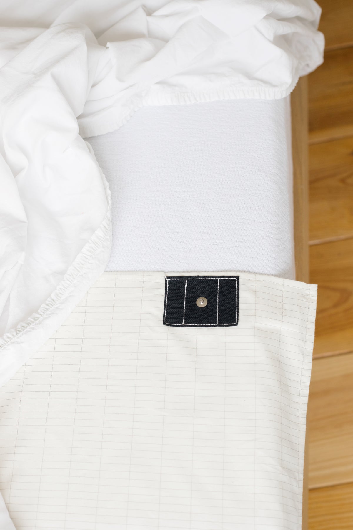 Drap de mise à la terre Earthle ouvert sur le lit avec le bouton pression pour le câble, 203 x 99 cm