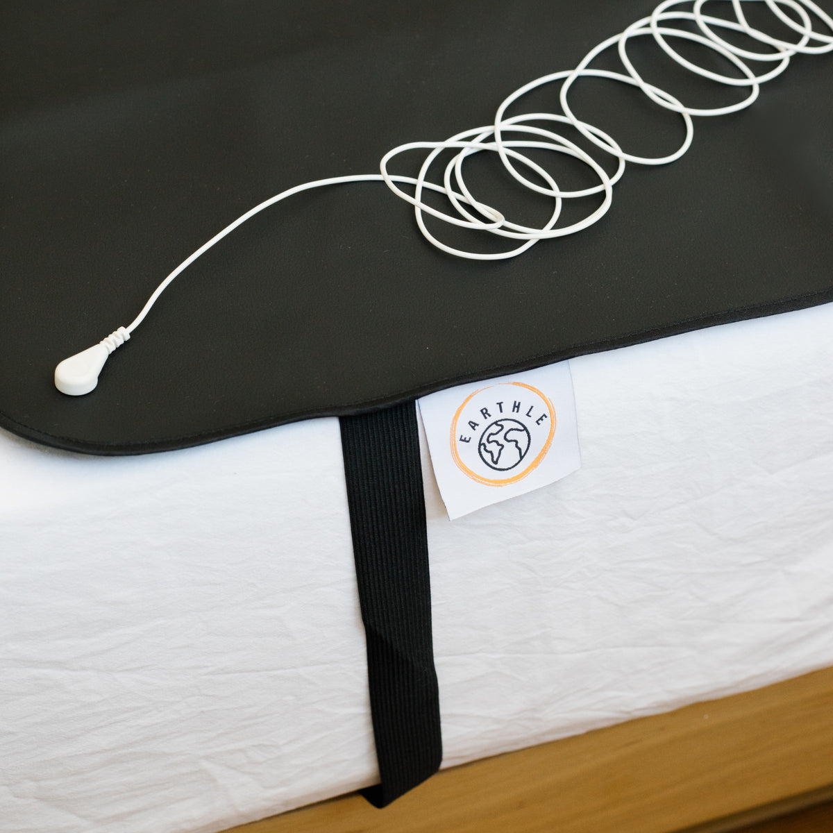 Câble de mise à la terre enroulé sur le tapis de sommeil noir dans un lit fait