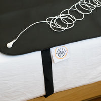 Câble de mise à la terre enroulé sur le tapis de sommeil noir dans un lit fait