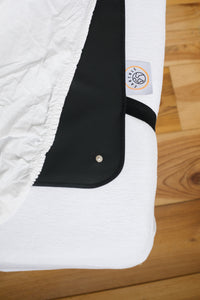 Tapis de sommeil de mise à la terre déplié sur le lit, étiquette de marque et bouton pression visibles