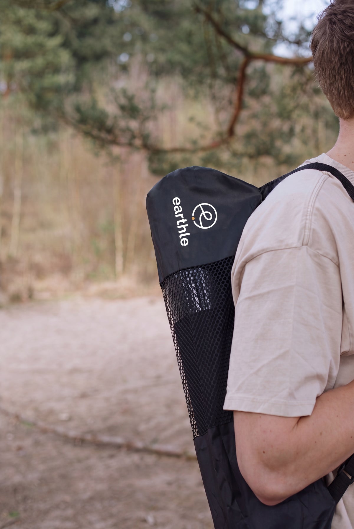 Quelqu'un porte le tapis de yoga de mise à la terre Earthle dans son sac sur le dos, dehors dans la forêt