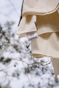 Drap de mise à la terre Earthle mis à sécher sur une branche de pin, avec l'étiquette visible, 203 x 180 cm